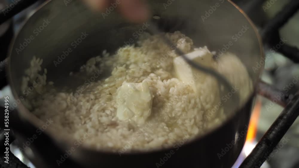 Cooking rice with butter in metal pot to prepare risotto, close up Cooking rice with butter in metal pot to prepare risotto, close up