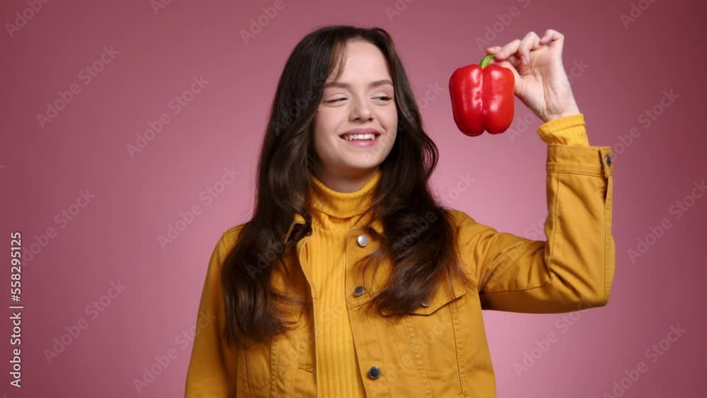 Close-up of female vegetarian enjoying fresh bell pepper. Portrait of young gardener holding healthy vegetable indoors. High quality 4k footage