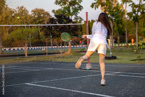 woman playing badminton in the park. urban asian sporty female having fun outdoor sports and game activity concept.