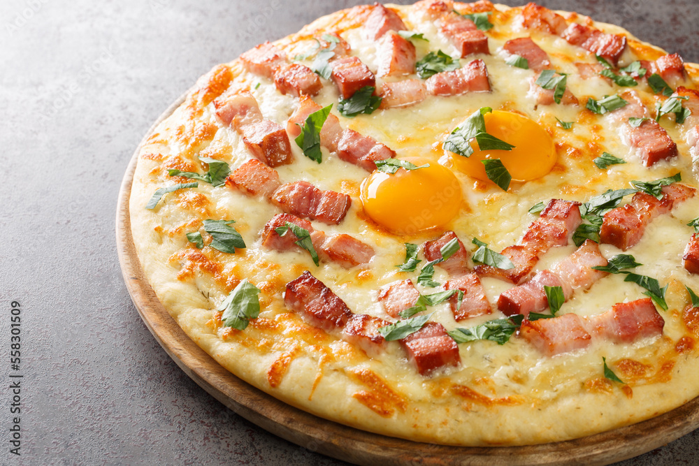 White pizza carbonara with egg, cream, bacon, cheese and herb closeup on the wooden board on the table. Horizontal White pizza carbonara with egg, cream, bacon, cheese and herb closeup on the wooden board on the table. Horizontal