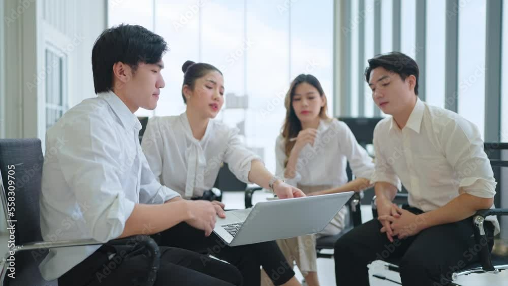 Team of Asian young business people meeting and discussing using laptop showing data in office Team of Asian young business people meeting and discussing using laptop showing data in office