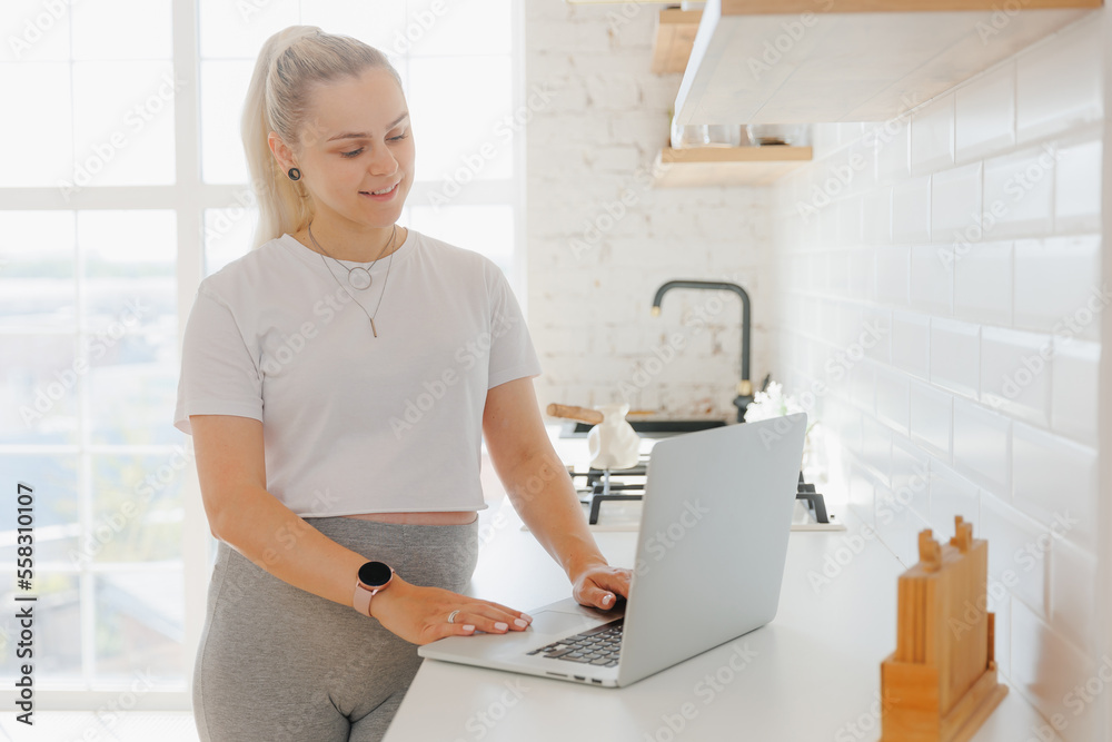 Young pregnant woman freelancer working on computer at home white kitchen. Remote work lifestyle Young pregnant woman freelancer working on computer at home white kitchen. Remote work lifestyle