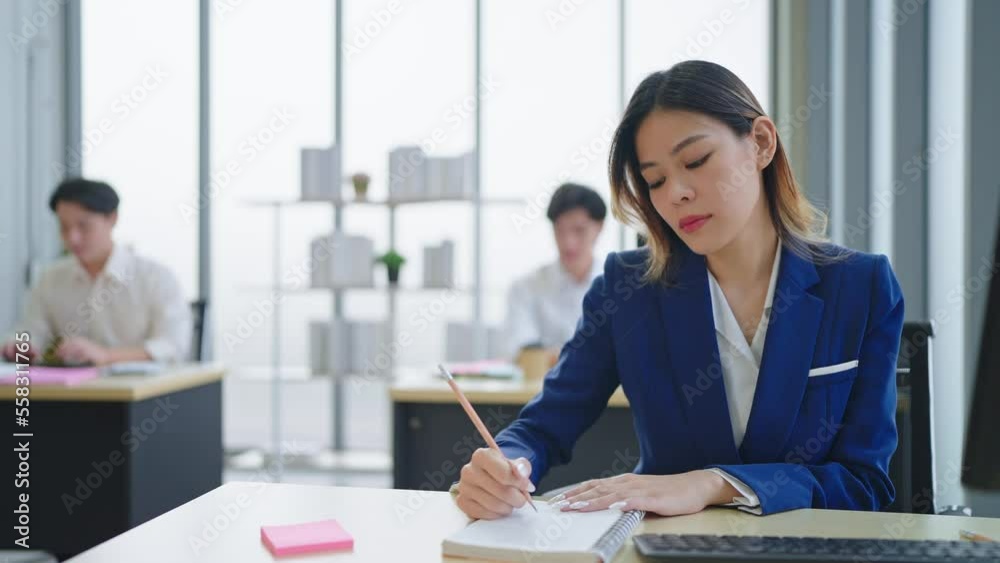 Asian woman employee wearing a suit working and using computer on desk in office Asian woman employee wearing a suit working and using computer on desk in office