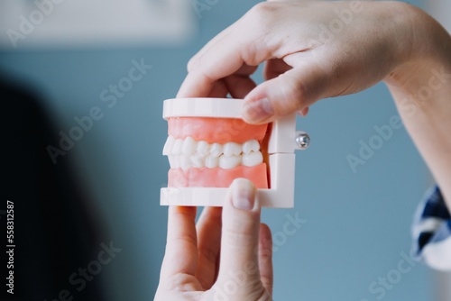 Stomatology concept, partial portrait of girl with strong white teeth looking at camera and smiling, fingers near face. Closeup of young woman at dentist's, studio, indoors
