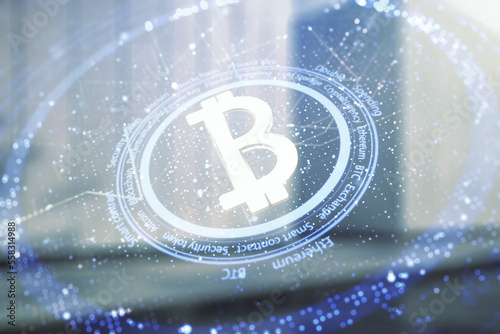 Double exposure of creative Bitcoin symbol hologram on modern business center exterior background. Cryptocurrency concept