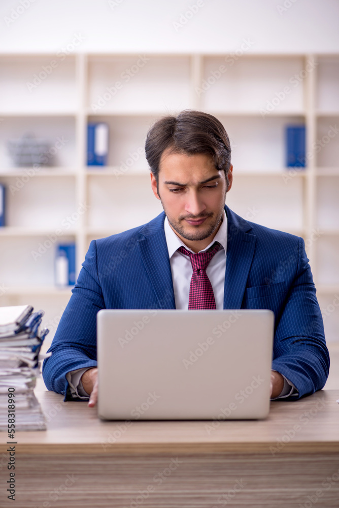 Young male employee and too much work in the office Young male employee and too much work in the office