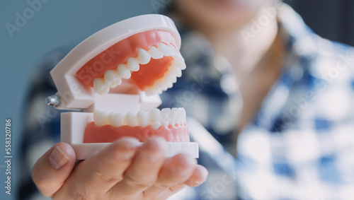 Stomatology concept, partial portrait of girl with strong white teeth looking at camera and smiling, fingers near face. Closeup of young woman at dentist's, studio, indoors