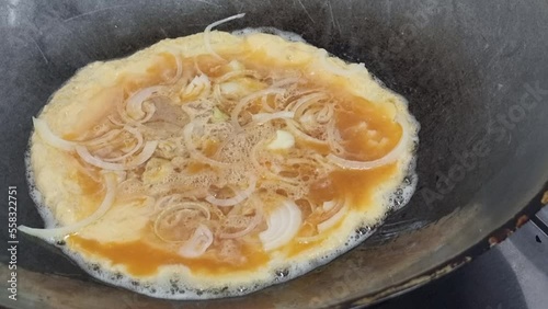 Omelet with onion on hot pan on food background