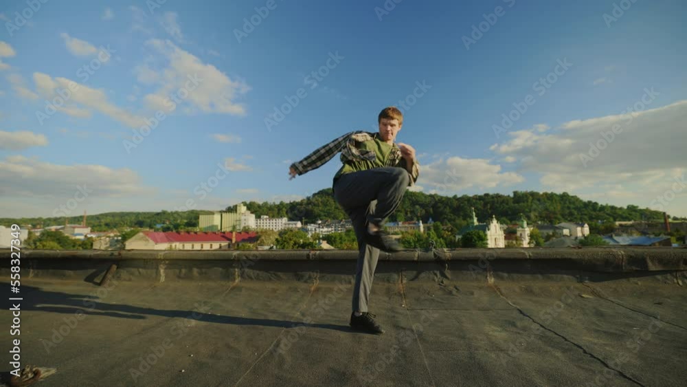 Caucasian handsome dancer performing hip hop outside on the roof. Brunette man enjoying dance,doing jumping movements. Male performer dancing skills. Dance, body, moves, action concept Caucasian handsome dancer performing hip hop outside on the roof. Brunette man enjoying dance,doing jumping movements. Male performer dancing skills. Dance, body, moves, action concept