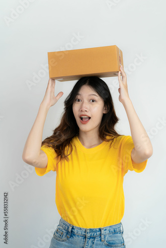Young Asian woman holding a box with a charming smile Isolated on white background. Online SME business and delivery concept.
