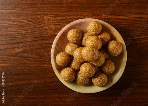 Til Laddu served in a bowl on wooden background, shot from above. Nutritious and healthy Indian traditional sweet. photo