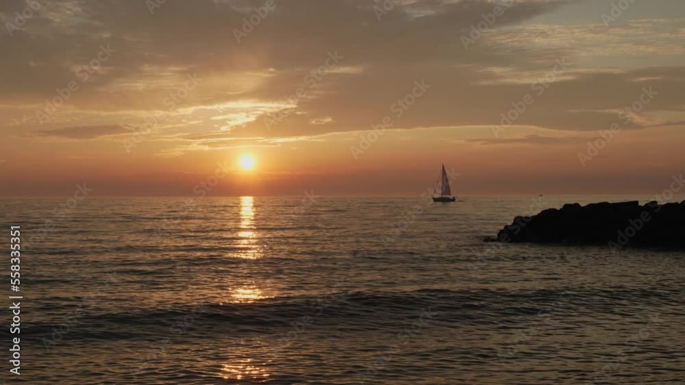 Wide static shot of a sailboat sailing off into the sunset. Wide static shot of a sailboat sailing off into the sunset.