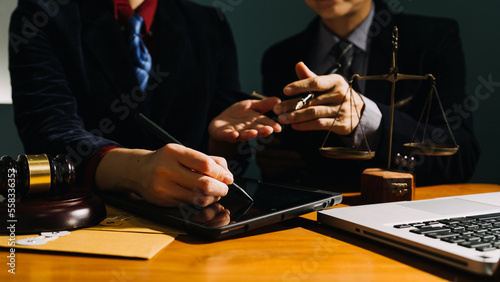 Business and lawyers discussing contract papers with brass scale on desk in office. Law, legal services, advice, justice and law concept picture with film grain effect