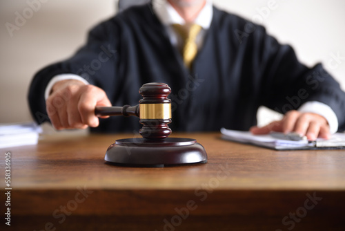 Judge passing sentence by hitting with gavel closeup photo