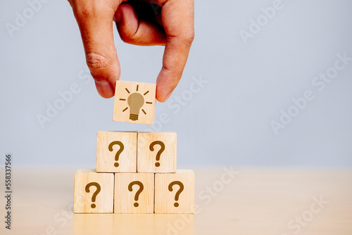 Hand holding wooden cube block in question mark what does it mean on cement table background A column of marked wooden blocks was discovered as the answer. copy space,FAQ frequently asked questions.