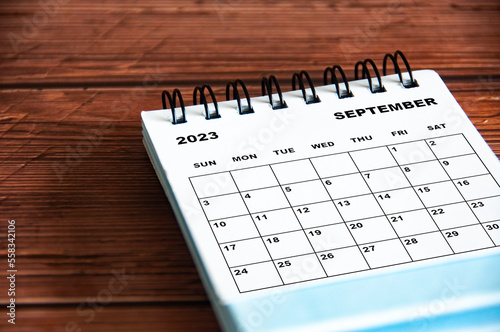 September 2023 white desk calendar on wooden table background. Calendar concept and copy space