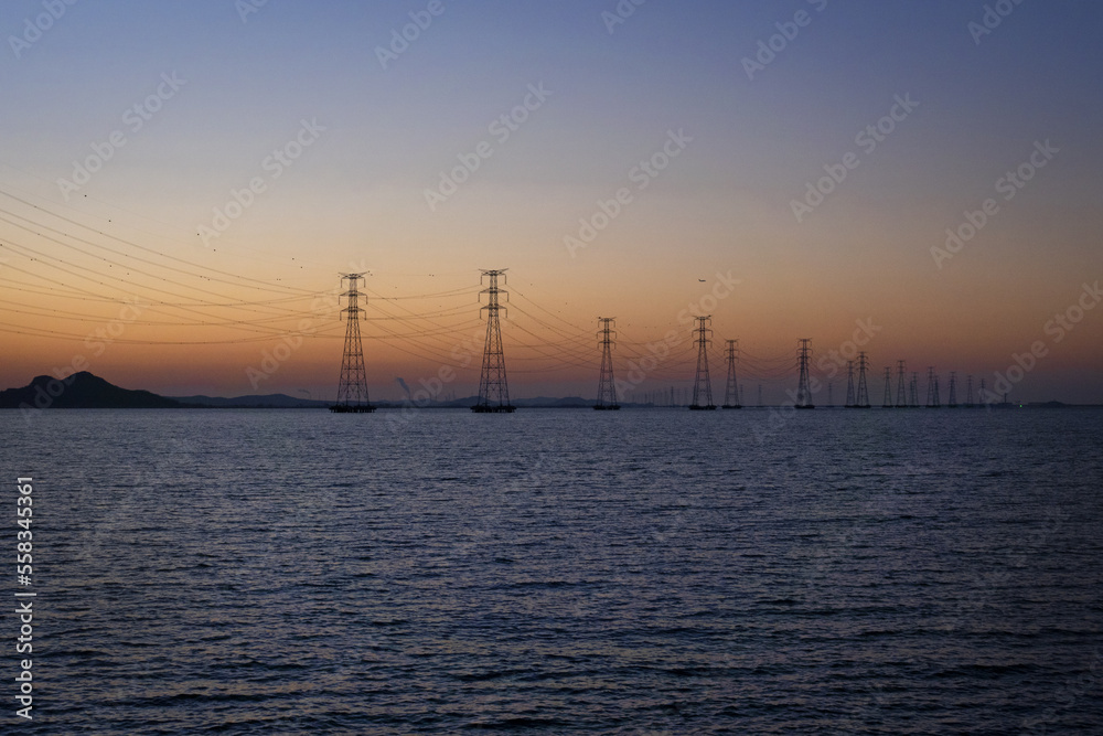해지는 저녁 노을과 바다 위에 설치된 송전탑