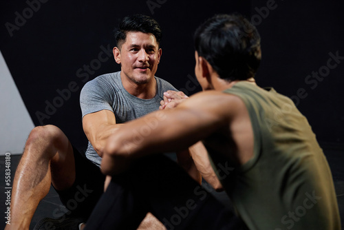 young athletic men meeting in the gym and shaking hands after workout