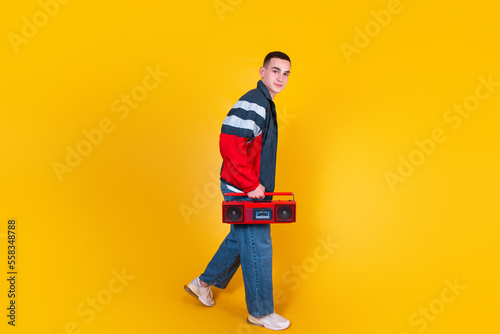 A handsome guy in the style of the 90s with a boombox on a yellow background © Valeriia