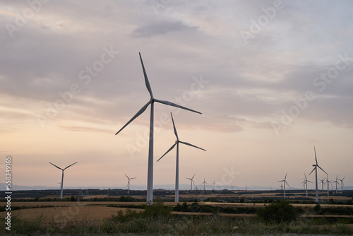 Silhouettes of Wind turbines farm generate energy power electricity during the evening. The sun goes down.