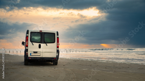 Camper van driving next to the wadden sea at low tide, traveling at the beach of Romo in Denmark, adventure vacation und lifestyle photo