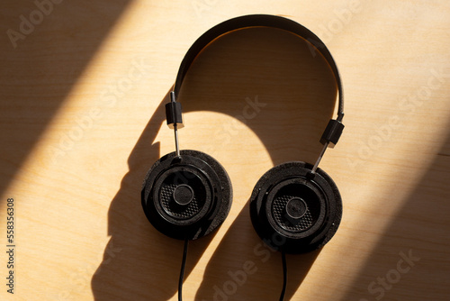 Black large headphones for comfortable listening to music and podcasts on a wooden background. Background for a list of music on a sunny autumn day. Listen to podcasts
