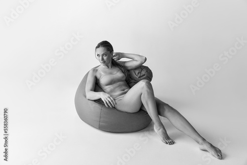 Black and white photography. Portrait of beautiful, slim woman sitting on floor pillow in underwear. Relaxation and well-being