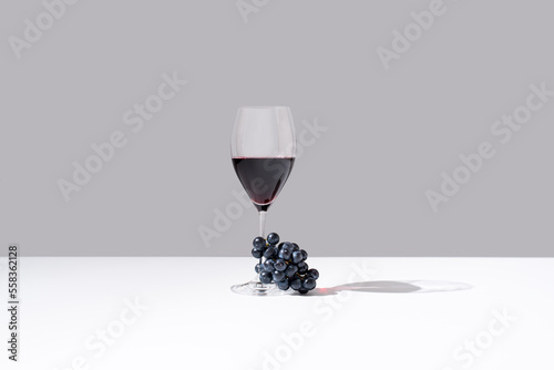 Tela Copa de vino tinto y racimo de uvas negras sobre fondo gris