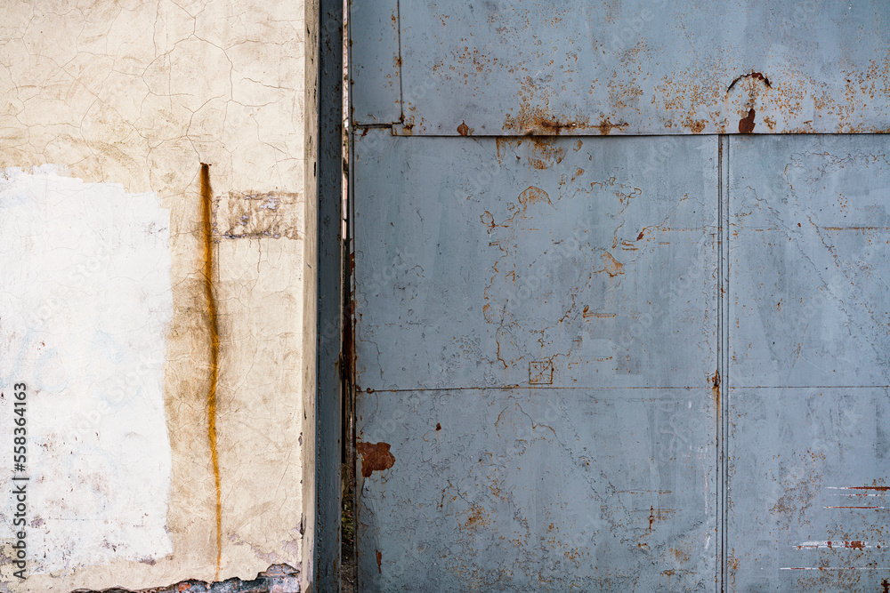 Huge grey rusty iron gate near the wall. Private territory. Factory. Control. Checkpoint. Metallic. Prohibition. Old warehouse. Entry. Entrance Huge grey rusty iron gate near the wall. Private territory. Factory. Control. Checkpoint. Metallic. Prohibition. Old warehouse. Entry. Entrance
