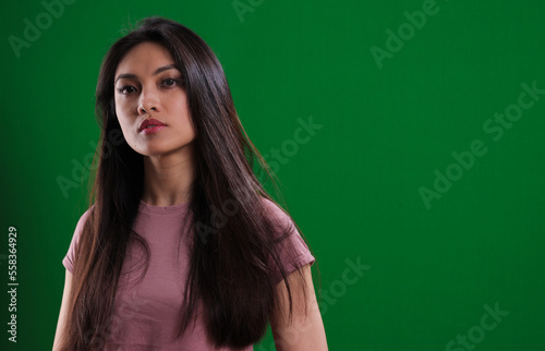 Young confident woman against a green background - studio photography