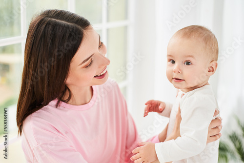 A young mother is tender with a newborn, little son, time together.