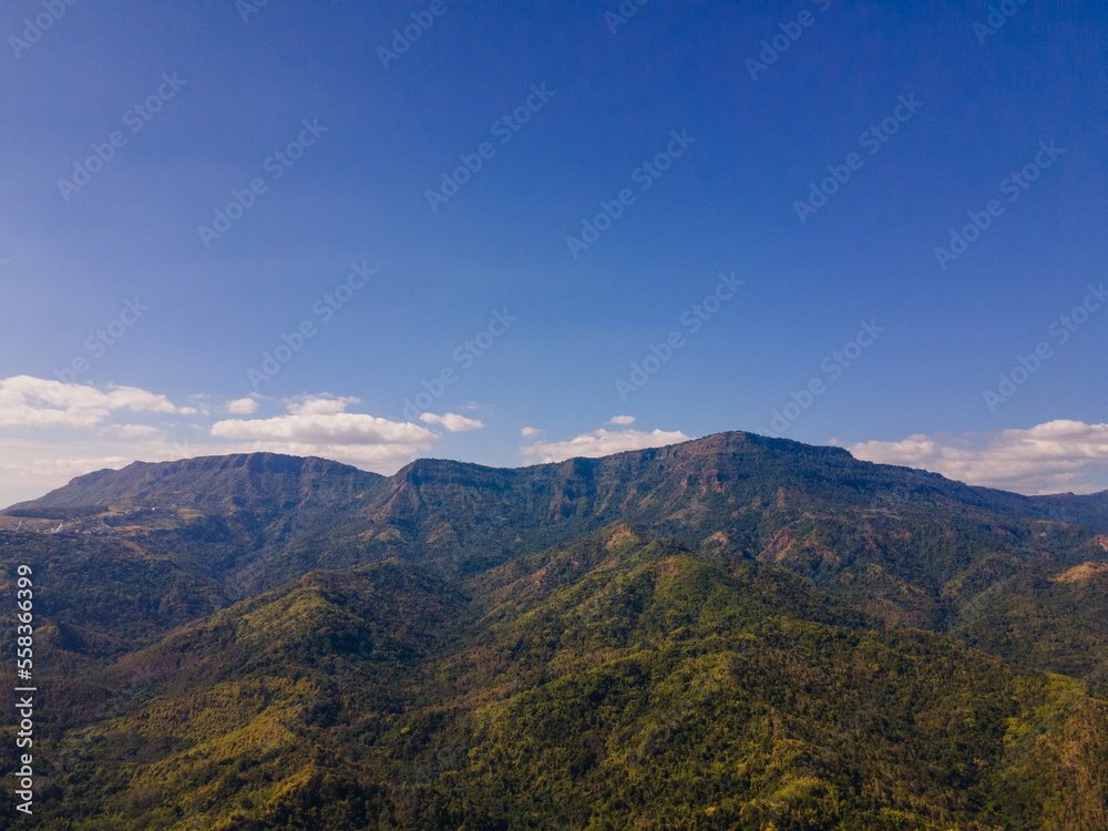 the aerial view of the mountain peak and the cliffs near the green forest