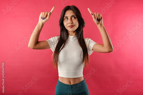 Young beautiful woman wearing ribbed crop isolated over red background look pointing up upset, feel jealous, regret, missing good opportunity, staring unhappy top advertisement. Unhappy and depressed.