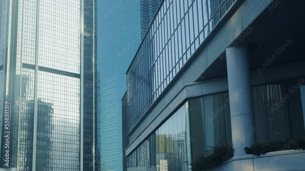 Abstract modern business architecture. Walls made of glass and steel with reflections of buildings and blue sky.