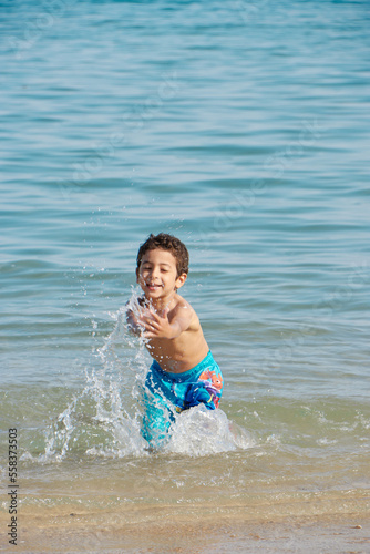 Happy child playing in the sea. Kid having fun outdoors. Summer vacation and healthy lifestyle concept. 