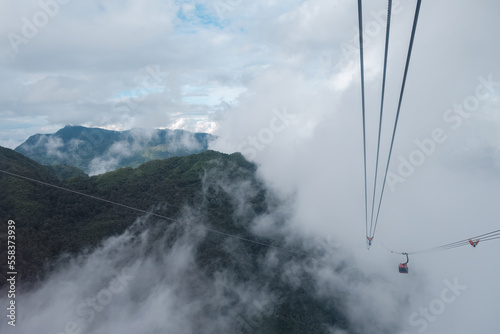 Cable car carries passenger moving on the mountain among the foggy in cloudy day at Sapa