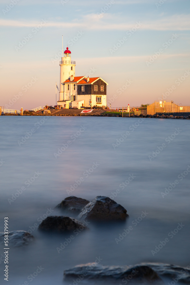 paard van marken lighthouse on marken island in golden hour with blue sky and rocks in the foreground