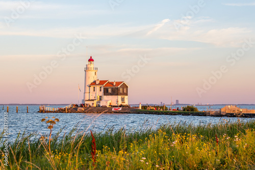 paard van marken lighthouse on marken island in golden hour with blue sky and sea with grass in foreground photo