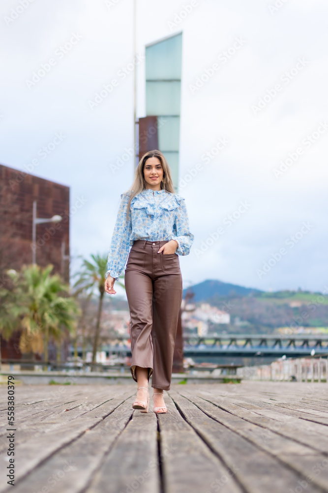 Portrait of young woman walking in a park in the city, lifestyle concept, blue shirt