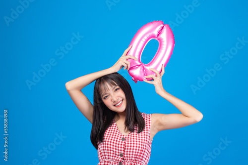 Happy new year and Merry Christmas concept. Beautiful young asian woman with balloons number 0 on blue background.