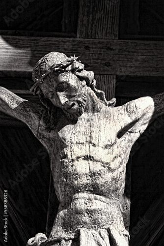 Close-up details of wooden carved Jesus Christ on the cross- selective focus and black and white tones.