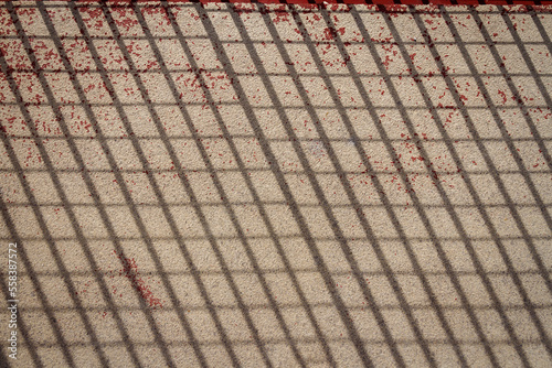 Net shape shadow of metal fence on cement floor