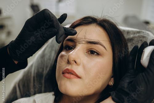 The make-up artist plucks eyebrows with a thread close-up. Women's cosmetology in the beauty salon.