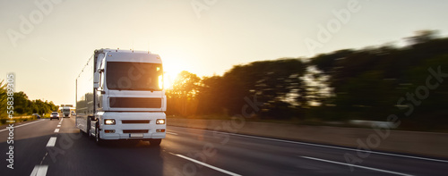 Obraz na płótnie Cargo truck with cargo trailer driving on a highway. White Truck delivers goods in early hours of the Morning - very low angle drive thru close up shot. fast motion blur effect w salonie