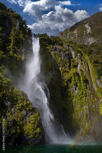 Impressive waterfall at Milford Sound New Zealand. Mountains and coast in Fjordlands. Dramatic. 