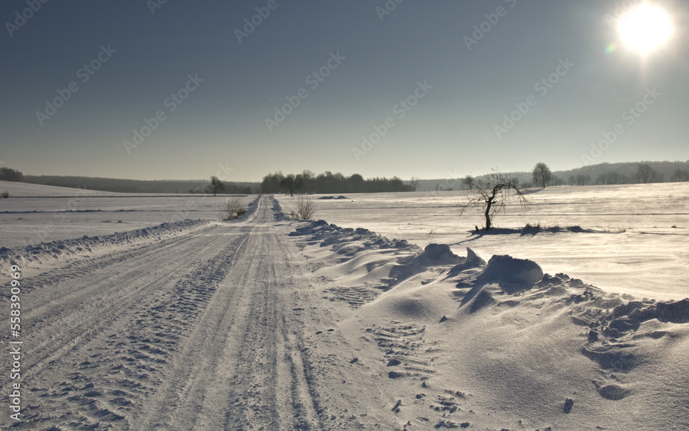 Winter road. Winter landscape of road. Snowy winter on the countryside, black and white picture. Highway leading through snowy fields. Drifts on the road.