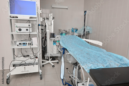 Large comfortable bed  couch in operating unit  covered with disposable sheet  is transformed into an operating table for operations. Endoscopic stand with monitor and equipment in operating room