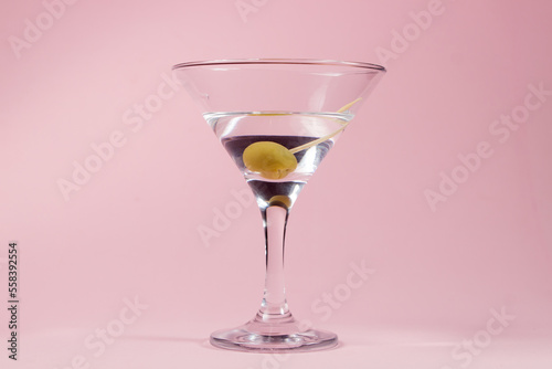 Martini glass with olive on a pink background. alcoholic drink