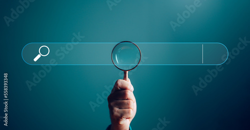 Businessman hand use magnifying glass Search On Virtual Screen Data Search Technology Search Engine Optimization. Searching for information. Using Search Console for data, info.