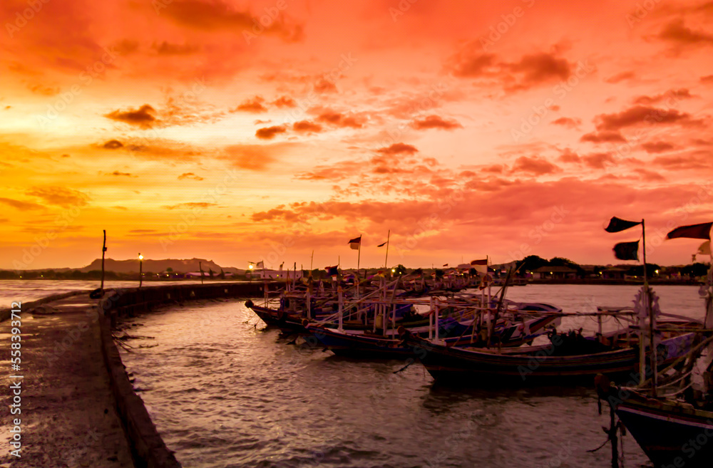 sunset over the harbor, the evening sky and the silhouettes of several fishing boats on the pier 